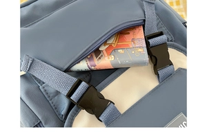Detail of navy and beige canvas backpack featuring outer zip pocket and plastic buckles