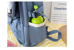 Detail of navy backpack side pocket featuring a green water bottle and adjustable strap