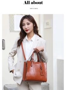 Close-up of caramel brown leather tote with embossed letters and adjustable strap