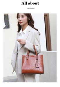 Close-up of caramel tote bag featuring embossed letter texture and leather hangtag