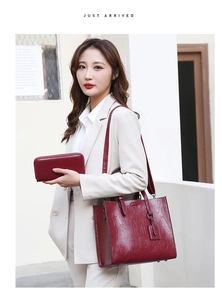 Detail view of deep red embossed tote bag and matching wallet set on a stylish model