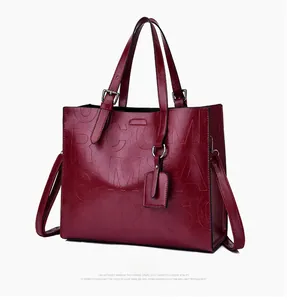 Detail view of large burgundy tote bag with embossed letters and adjustable strap