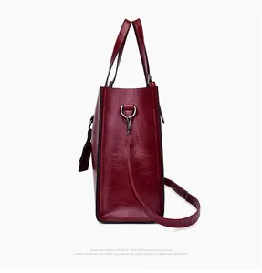 Detail view of burgundy tote side with embossed oil-wax texture and silver metal rings