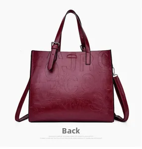 Macro shot of dark red tote bag featuring detailed letter embossing and glossy texture