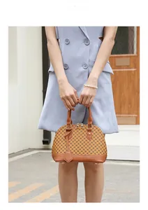 Close-up of shell-shaped handbag with monogram print and brown leather handles