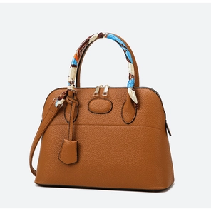 Macro shot of brown lychee grain leather tote bag with elegant silk scarf wrapped handle