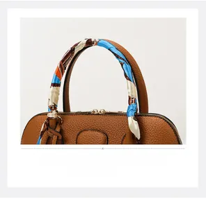 Detail of brown litchi pattern leather tote handle with a blue geometric print silk scarf