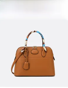 Detail of caramel lychee leather handbag featuring a decorative floral silk scarf handle