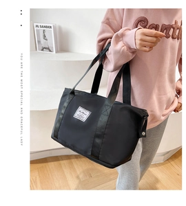 Close-up of black nylon travel tote featuring a fashion label on a minimalist background