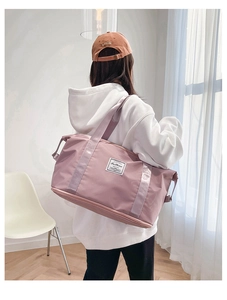 Rear view of a model carrying a lavender large capacity travel bag for fitness and sports