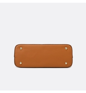 Close-up of caramel leather handbag bottom with four protective gold metal feet studs