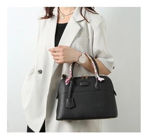 Detail of black pebbled leather handbag featuring shell shape and pink floral scarf handle