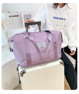 Close-up of lilac travel bag with bottom zipper extension on a white textured suitcase