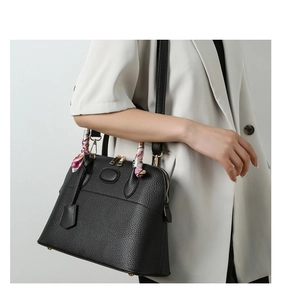 Close-up of black lychee grain tote with gold hardware and pink decorative silk scarf