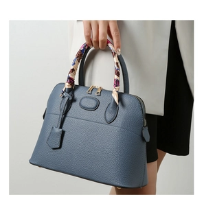 Close-up of grey-blue leather handbag handle wrapped with colorful floral silk scarf detail