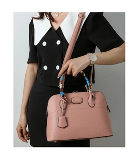 Close-up of pink pebbled leather handbag with silk scarf detail and golden base studs