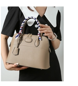 Detailed macro view of lychee grain leather shell bag with striped scarf handle wrap