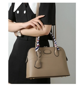 Detail of khaki shell handbag with pebbled leather texture and striped silk scarf wrap