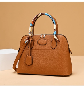Detail of caramel pebbled leather handbag featuring a rainbow silk scarf on the handle