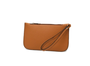 Close-up of tan lychee grain leather wristlet bag with gold zipper and minimalist design