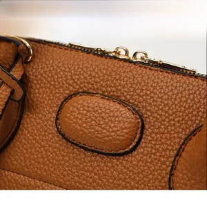 Close-up of brown lychee grain leather handbag with gold zipper and fine hardware details