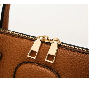 Detail of high-quality caramel lychee leather and dual golden metal zippers on the handbag
