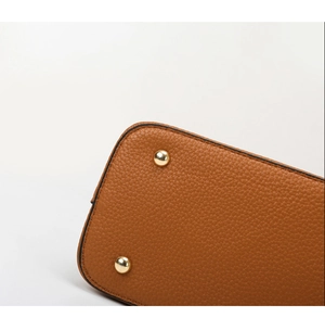 Close-up of brown lychee leather bag bottom with gold metal feet and neat stitching