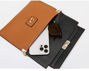 Detail showing the internal capacity of the brown flap bag with a phone and sunglasses