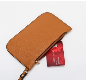 Detailed view of a brown pebbled leather coin purse with a gold zipper and carry strap