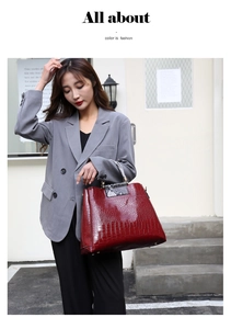 Detail of burgundy crocodile embossed leather handbag with contrasting snakeskin handles