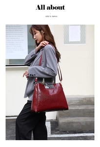 Detail of burgundy crocodile embossed tote bag held by model in professional grey suit
