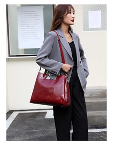 Detail of burgundy crocodile embossed tote bag with snakeskin flap and gold hardware