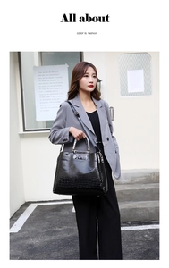Detail of black crocodile texture tote bag with snakeskin pattern handles and shoulder strap