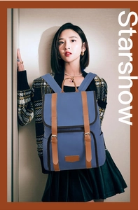 Detail of blue nylon backpack featuring brown leather straps and metallic buckle closure