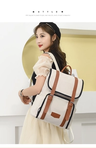 Detailed view of women's canvas backpack featuring contrast leather trim and top handle