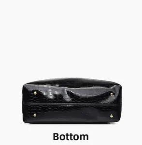 Detailed bottom view of black crocodile pattern bag with four gold metal protective feet