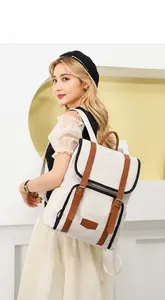 Detail of color-block backpack with brown leather straps and metallic buckle fasteners