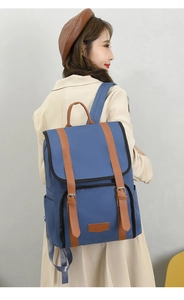 Deep blue nylon backpack with brown leather straps shown on a model in a beige coat