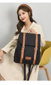 Detail of lightweight black nylon backpack with brown leather straps and metal buckles