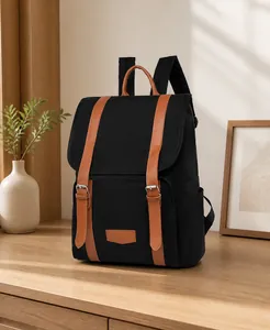 Detail view of black canvas backpack featuring brown leather straps and metallic buckles