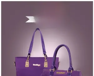 Detail of purple nylon tote set with gold metal logo and durable leather handles
