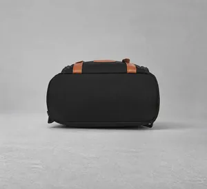 Detail view of the flat bottom design and brown accents on this black backpack