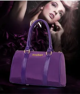 Detail of purple nylon tote bag with leather handles and gold metal hardware accents