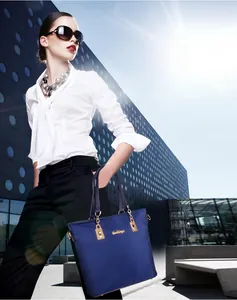 Close-up of navy nylon tote bag featuring gold metallic logo and premium leather handles