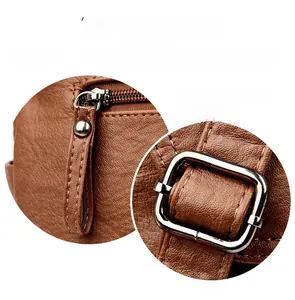 Close-up of brown litchi leather bag with polished bronze zipper and metal buckle