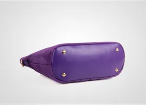 Detail view of large nylon tote bottom with premium faux leather base and gold metal feet