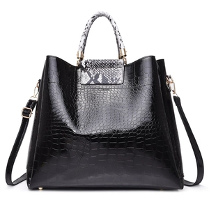 Black crocodile pattern tote bag with snakeskin accents and gold hardware on white background