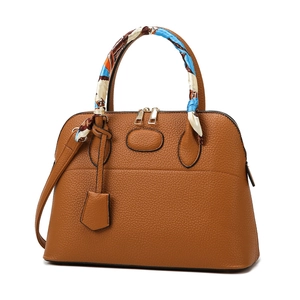 Classic tan leather handbag with decorative silk scarf and detachable shoulder strap