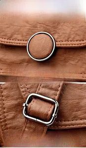 Close-up of vintage brown pebble leather texture with round metal hardware and adjustable buckle