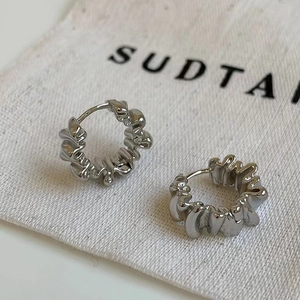 Close-up of irregular textured silver earrings on a minimalist cotton pouch